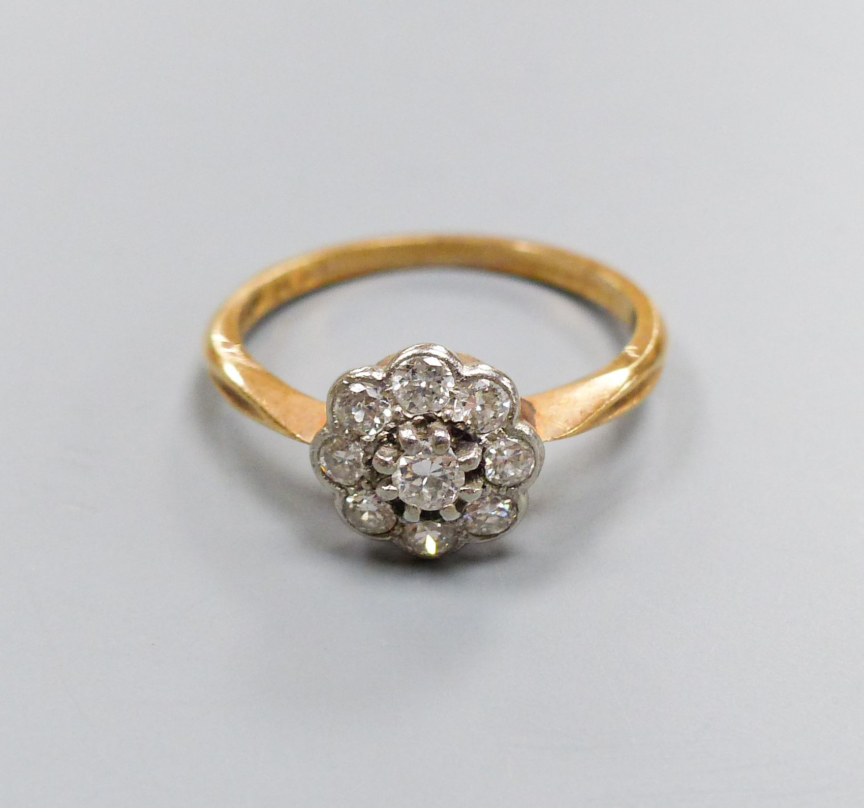 An 18ct & plat, circular diamond cluster set ring, size M/N, gross weight 2.5 grams.